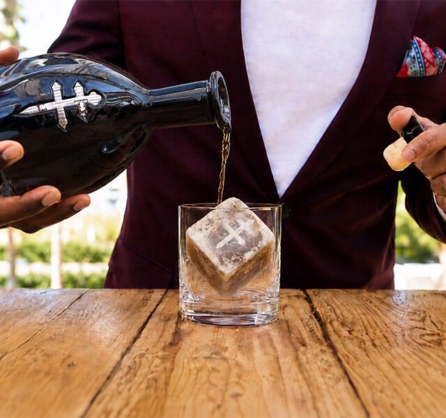 Bartender pouring D’USSÉ XO over a Coffee Uplifts People Café Con Leche coffee ice cube, creating a coffee-and-cognac beverage experience.