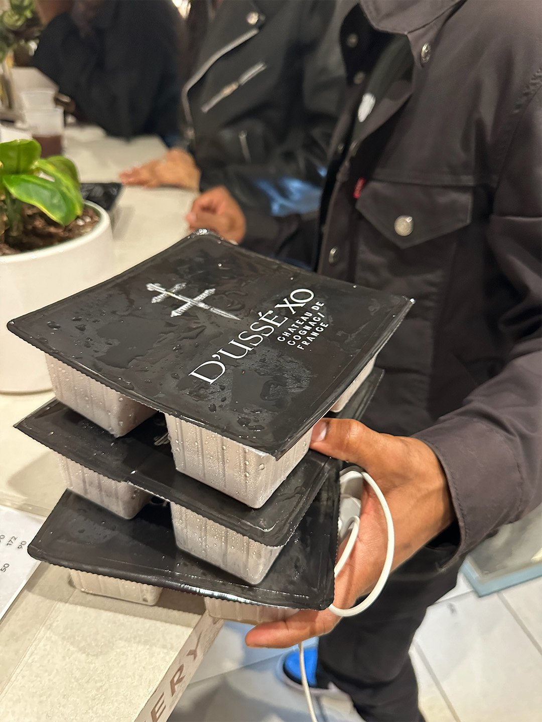 Channing Bailey holding stacked frozen D’USSÉ XO Coffee Cube packages prepared for hospitality service.
