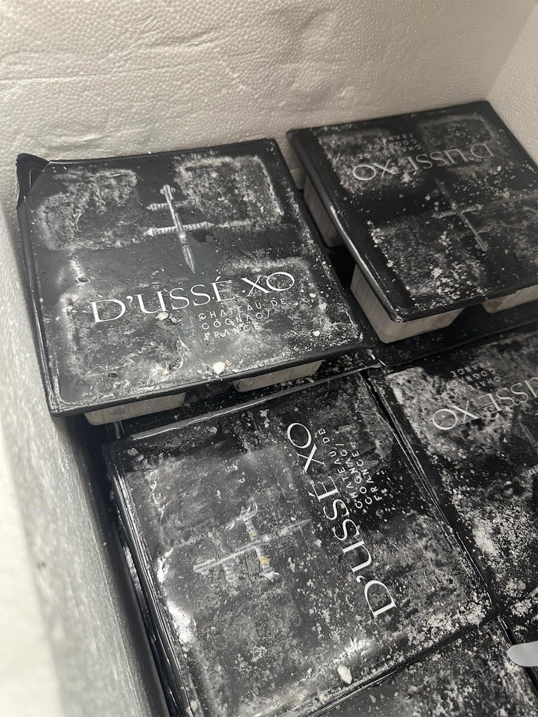 Packaged D’USSÉ XO Café Con Leche coffee cubes prepared for hospitality service, with branded black lids and frozen coffee cubes inside.